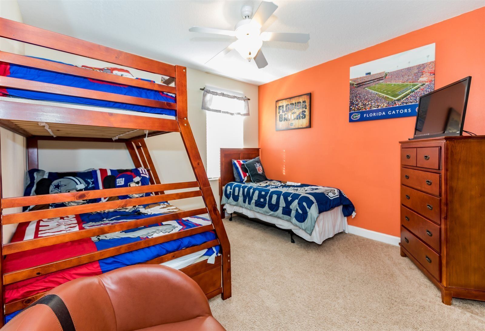 A bedroom with a bunk bed, a single bed, a dresser, and a ceiling fan.