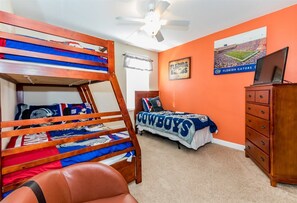 A bedroom with a bunk bed, a single bed, a dresser, and a ceiling fan.