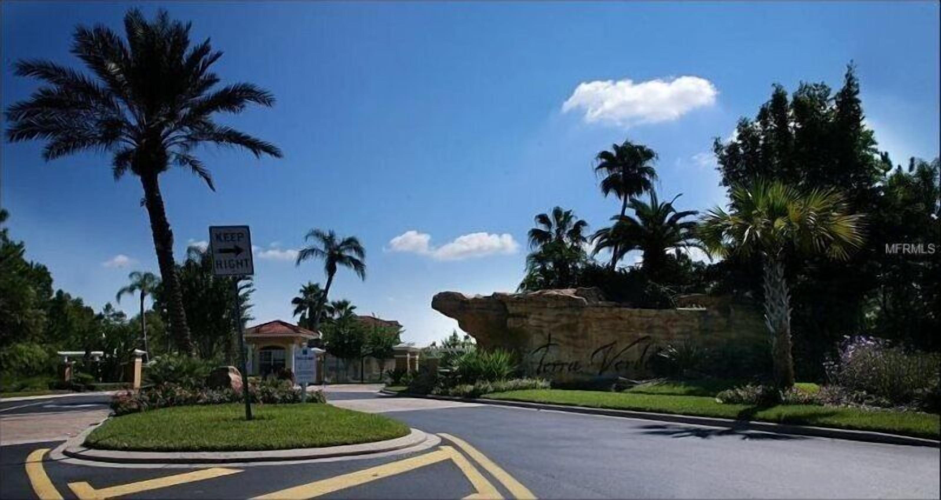 A residential area with a roundabout, palm trees, and a large rock formation.