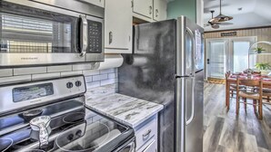 A kitchen with stainless steel appliances, a marble countertop, and a wooden dining table with chairs.