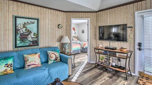 A living room with a blue sofa, a TV, and a wooden paneled wall.