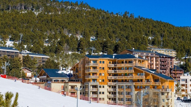 A ski resort with multi-story buildings, ski slopes, and a forested mountain backdrop. - 2 BR Apartment for 6 at L'Orée des Cimes (Les Angles)