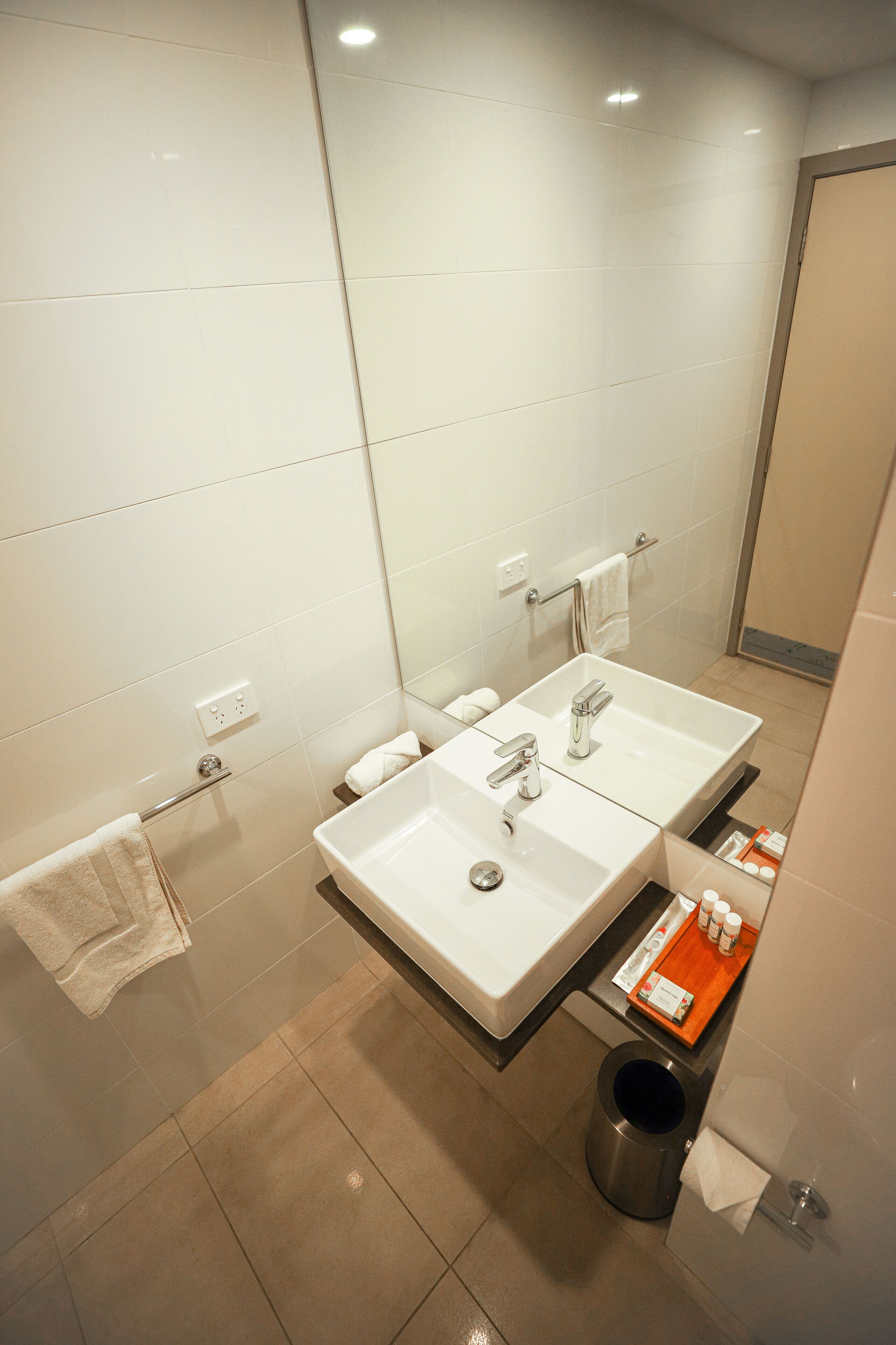 A modern bathroom with two sinks, a shower, and a toilet.