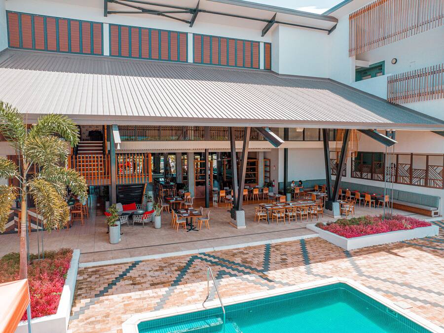 Un hotel con un espacio exterior cubierto, piscina y varias zonas de comedor.