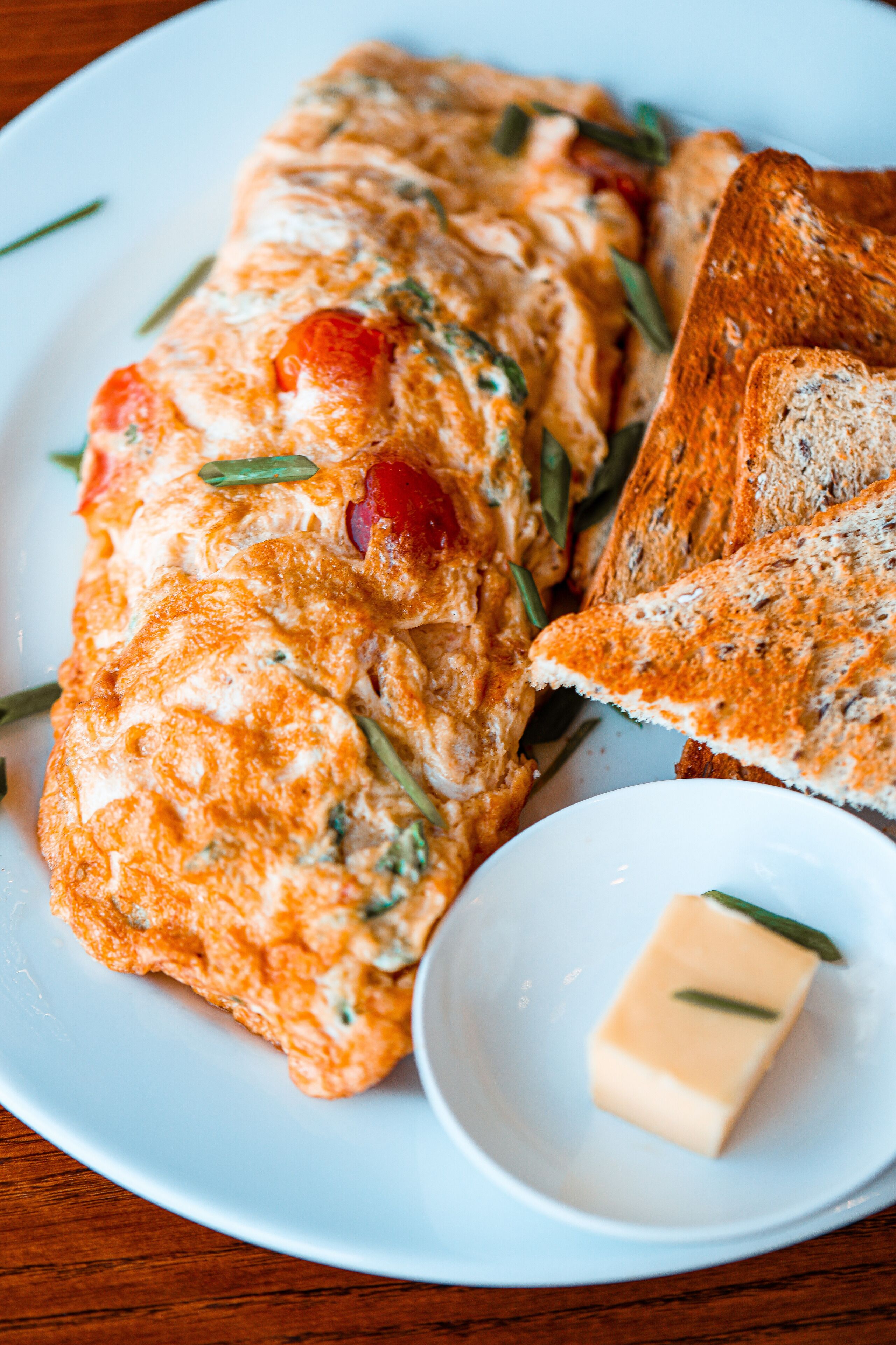 Ein Frühstücksteller mit einer Omelett, Toast und einer kleinen Butterportion.