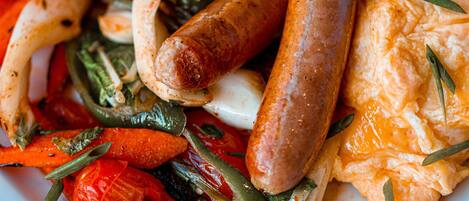 A plate of food including sausages, roasted vegetables, and a piece of toast with butter.