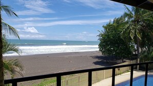 Blick auf einen Strand von einem Balkon, im Vordergrund ein Schwimmbad.