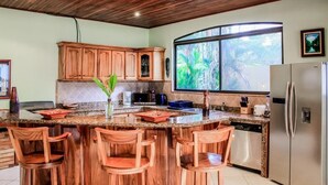 Eine Küche mit Holzschränken, einer Granit Arbeitsplatte und einem Edelstahlkühlschrank.