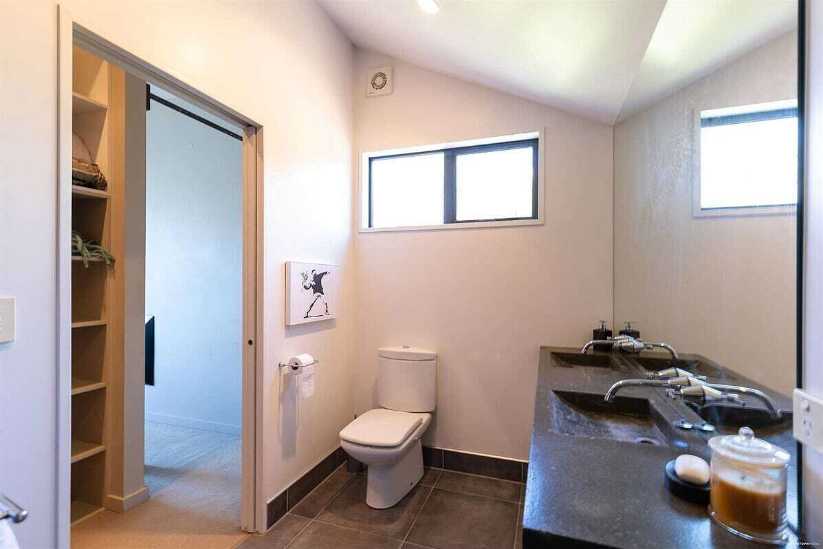 A bathroom with a toilet, sink, and a window.