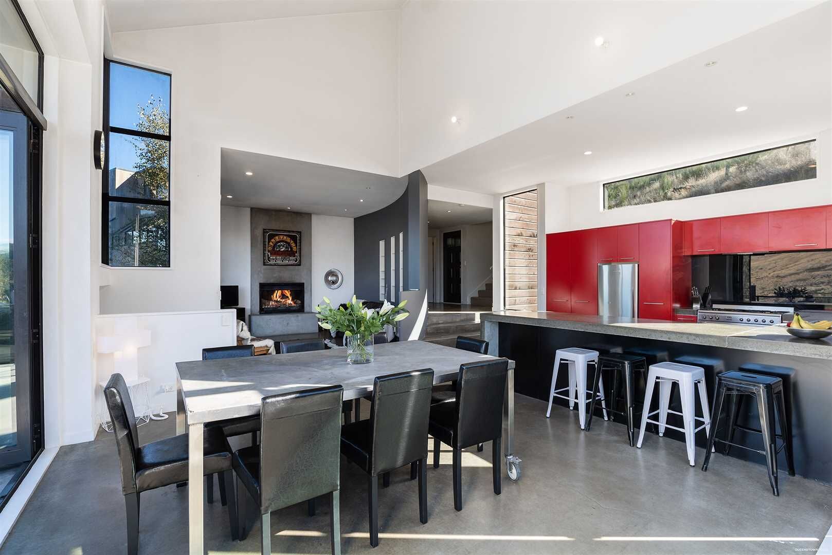 A modern kitchen with red cabinets, a large island, and a dining area with a table and chairs.