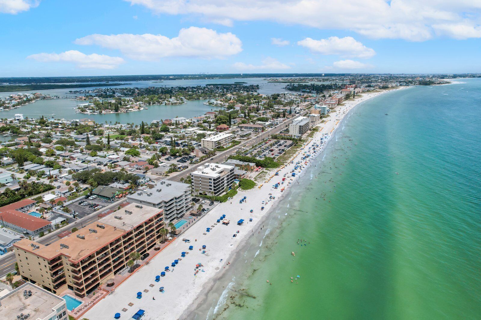 A coastal cityscape with a long beachfront, a marina, and dense urban development.