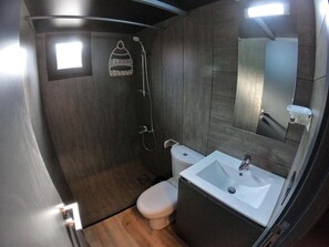 A compact bathroom with a shower, toilet, and sink. - The Getaway (Hrajel)