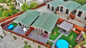 A residential property with multiple green-roofed buildings, a swimming pool, and a patio area with outdoor furniture. - The Getaway (Hrajel)
