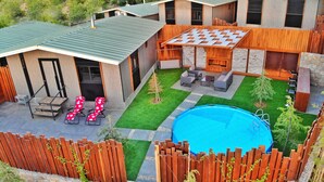 A modern outdoor patio area with a pool, seating, and a wooden fence. - The Getaway (Hrajel)