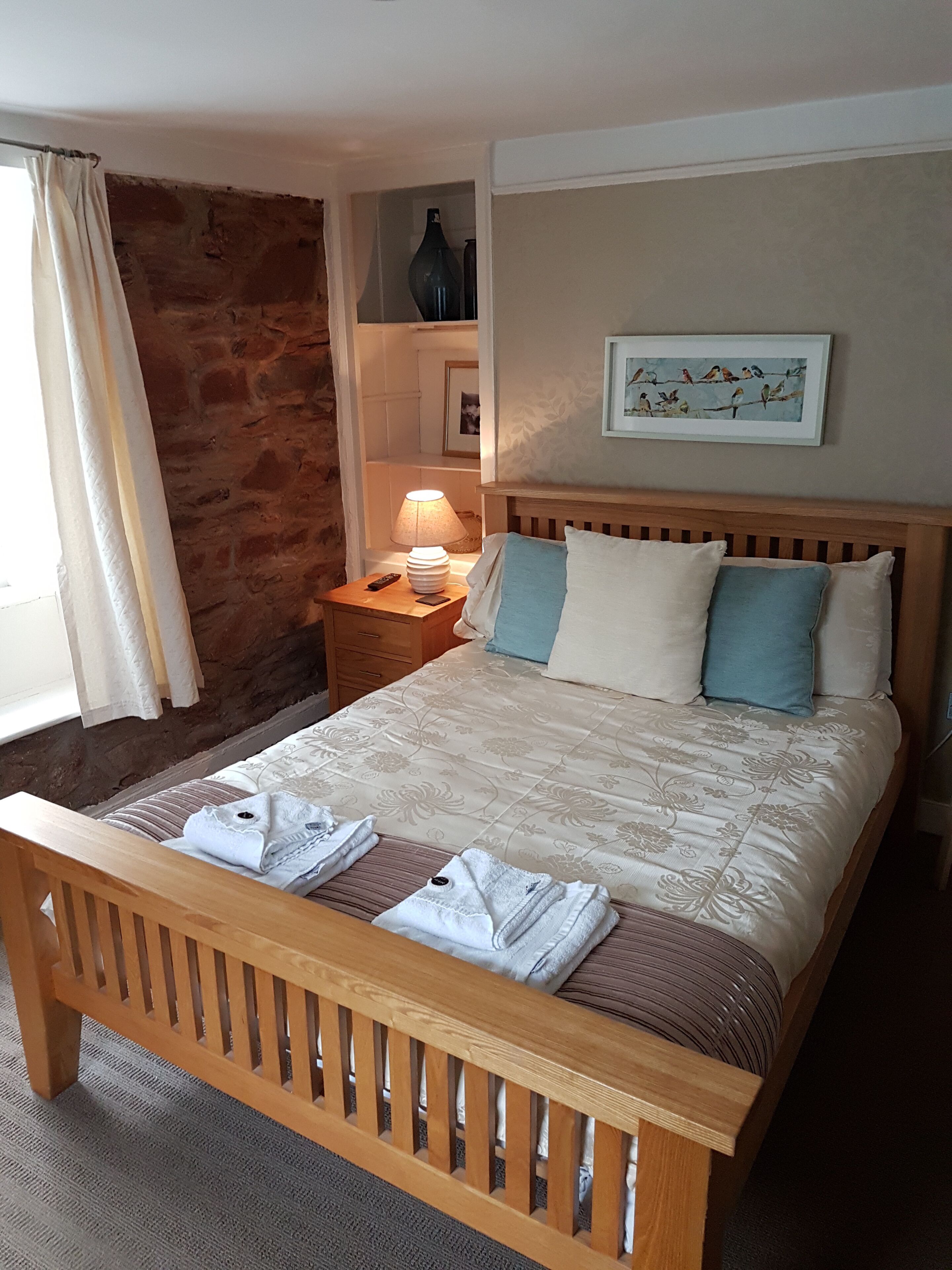 A neatly made bed with pillows, a bedside lamp, and a framed picture on the wall.