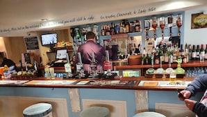 A bar with multiple beer taps, stools, and a variety of bottles. - Halfway House Inn (Torpoint)