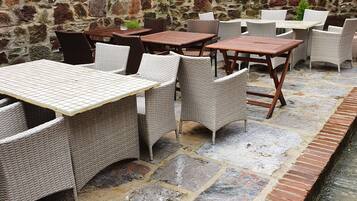 An outdoor patio with stone flooring, wicker furniture, and a wooden fence.
