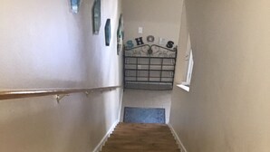 Una escalera de madera con barandilla que lleva a un rellano con un cartel decorativo.