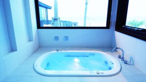 Une salle de bain moderne avec une baignoire sur pieds, une fenêtre donnant sur des palmiers et un sol carrelé.