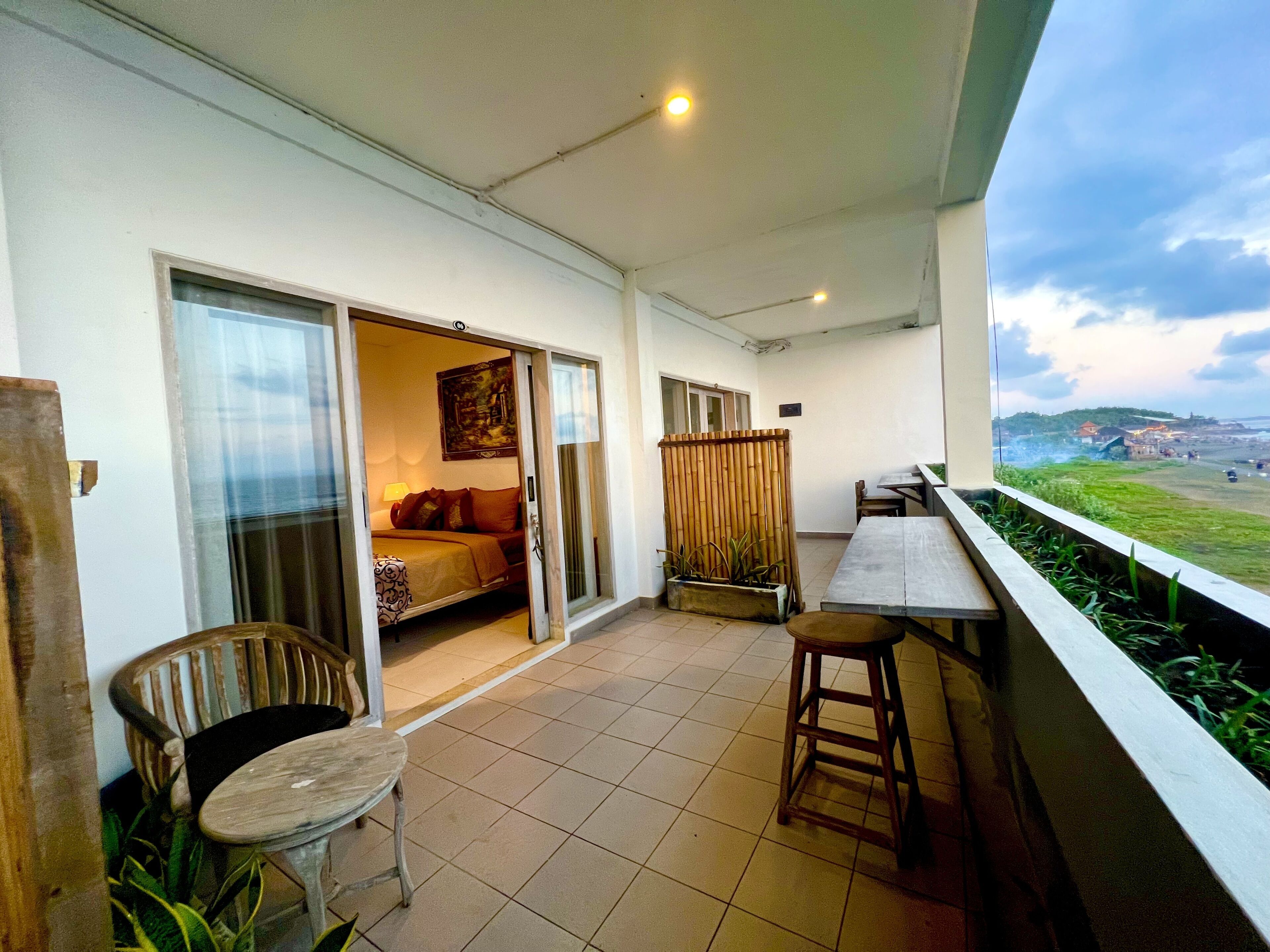 Un balcon avec un lit, une table et des chaises. On peut admirer le paysage depuis cet endroit.