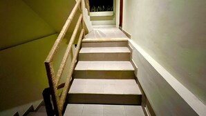 A staircase with a wooden handrail leading to a landing with a potted plant. -  Sau Bali Beach House Canggu (Pererenan)