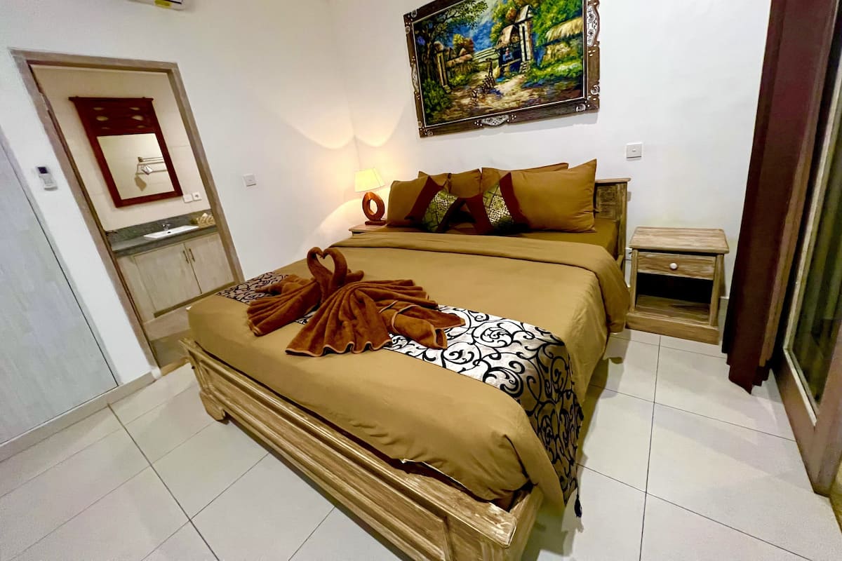 Une chambre d’hôtel avec un lit, une table de chevet, un tableau et une salle de bain visible.
