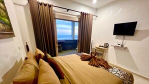 A hotel room with a bed, a TV, and a view of the sea. -  Sau Bali Beach House Canggu (Pererenan)