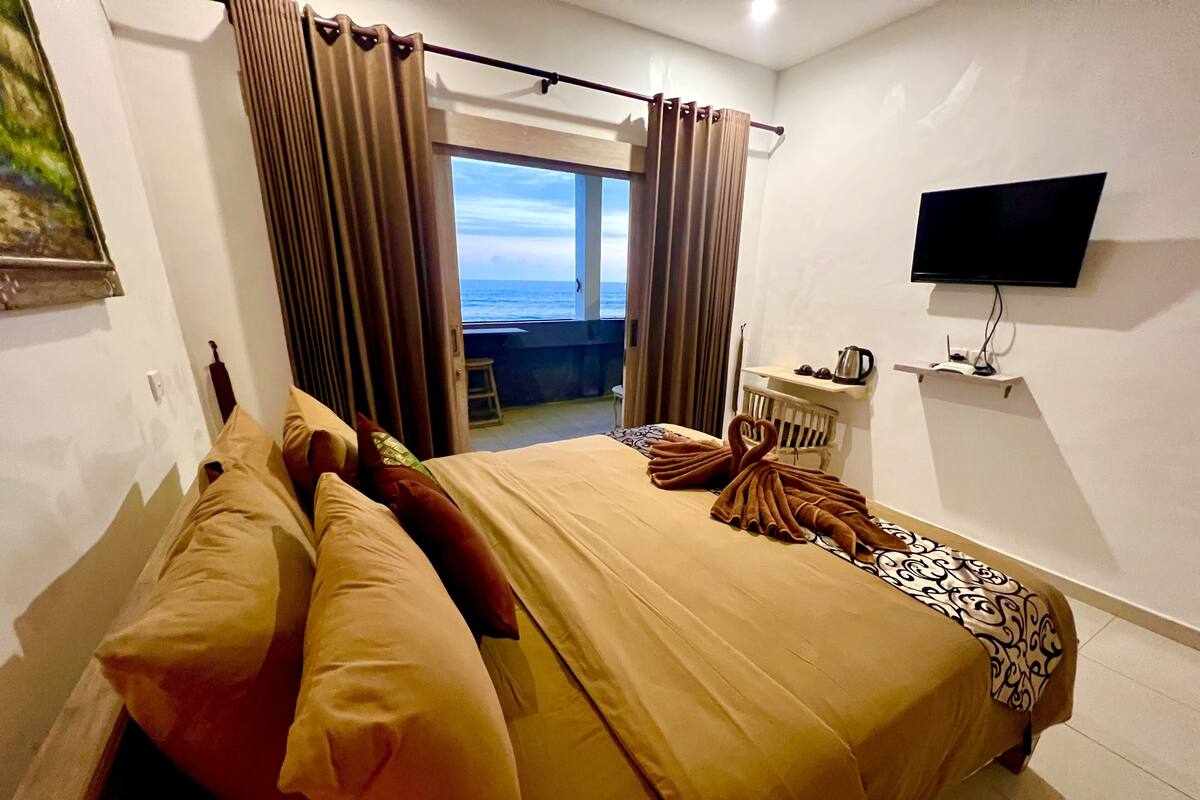 Une chambre d’hôtel avec un lit, une télévision et une vue sur la mer.