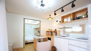 Eine moderne Küche mit weißen Schränken, einer Holzarbeitsplatte und einem eingebauten Backofen. In der Ecke steht ein kleiner Hocker und ein Mülleimer.