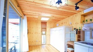 Eine moderne Küche mit Holzwänden und einem großen Fenster, einem eingebauten Backofen sowie einem kleinen Essbereich, der durch das Fenster sichtbar ist.