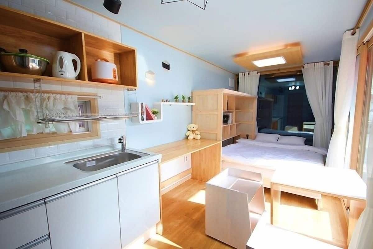 A compact, modern room with a kitchenette, a bed, and a small seating area.