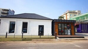 Ein modernes Gebäude mit weißer Fassade und schwarzem Dach, ausgestattet mit großen Fenstern und einem kleinen Eingang.