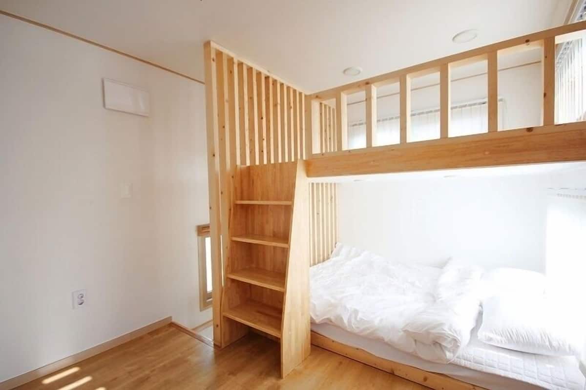 A bunk bed with a wooden ladder and a built-in shelf unit.