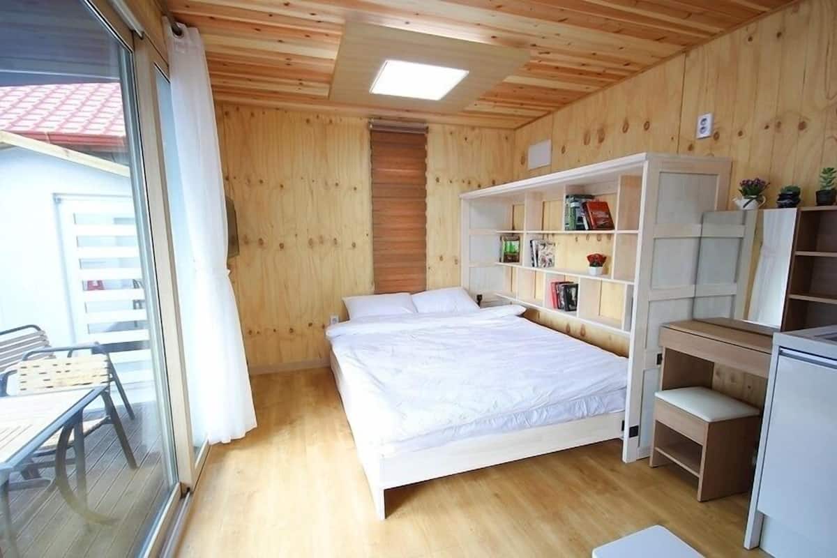 A bedroom with a bed, a white wardrobe, and a small desk.