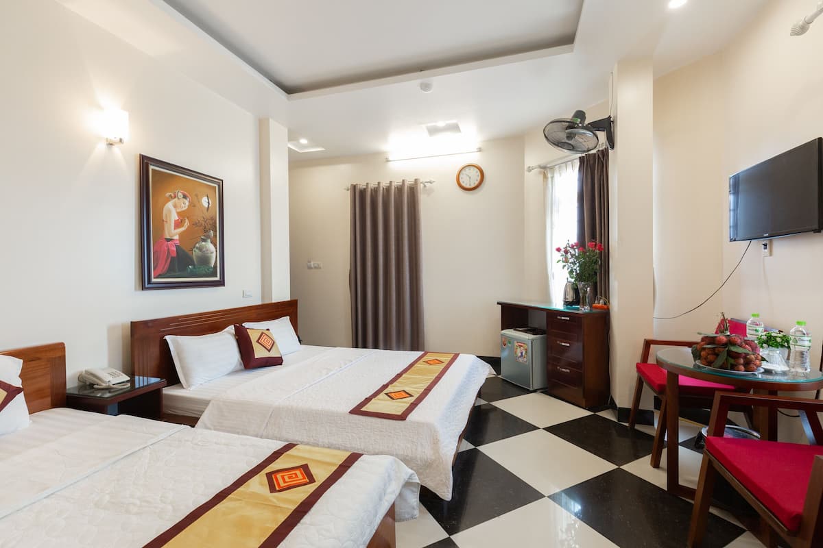 A hotel room with two beds, a desk with a chair, a television, a clock, and a window with curtains.