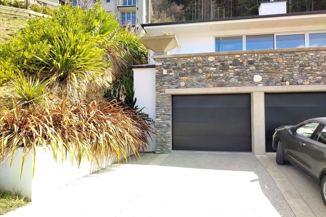 A modern house with a stone facade, a garage, and a parked car.
