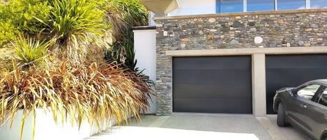 A modern house with a stone facade, a garage, and a parked car.