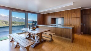 A modern kitchen with wooden cabinetry, a stainless steel countertop, and a large window offering a mountain view. - Design, Elegance and This Stunning View (Queenstown)