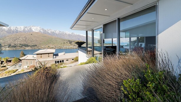 A modern building with large windows overlooking a lake and mountains. - Design, Elegance and This Stunning View (Queenstown)