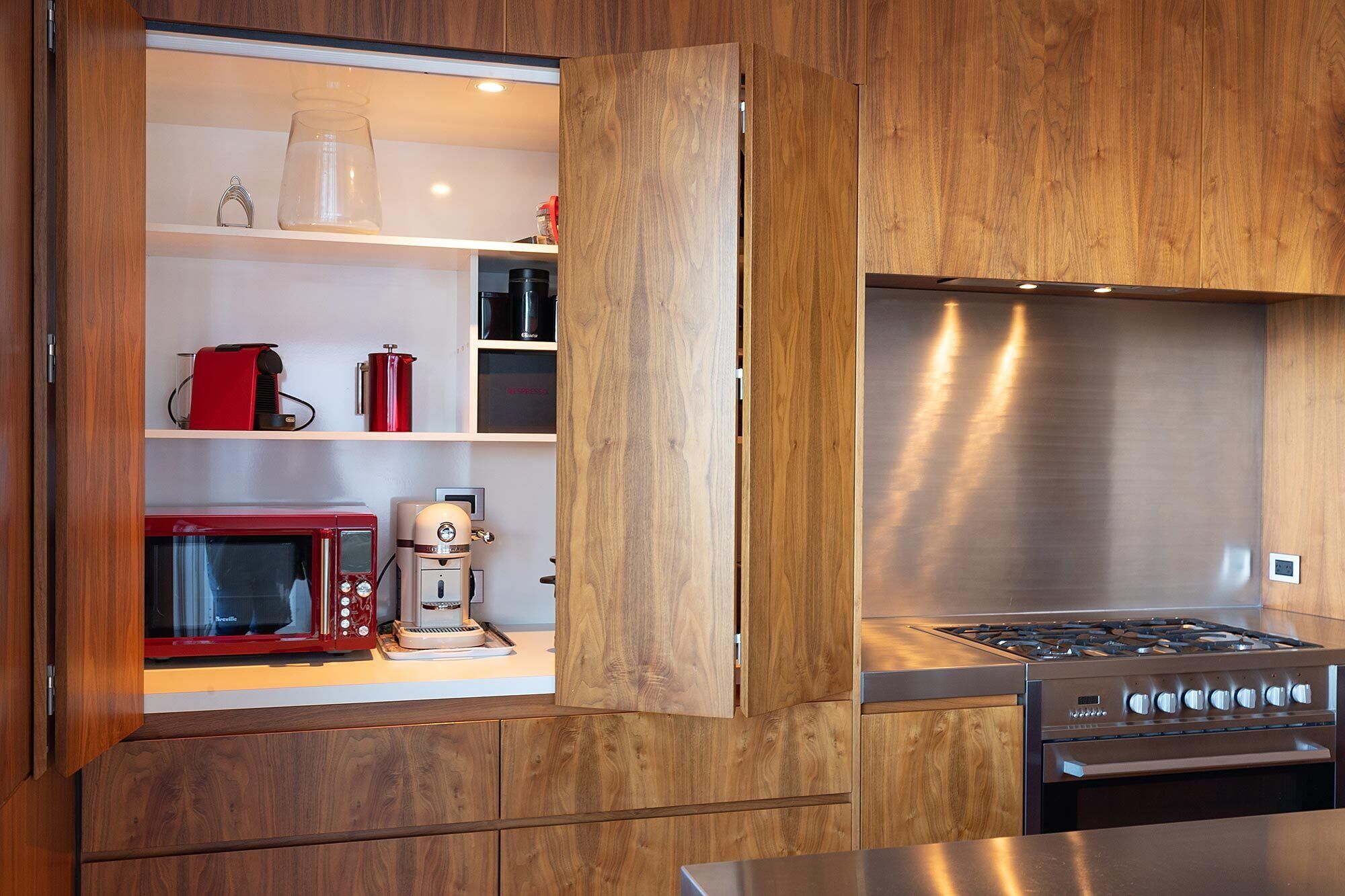 Une cuisine moderne avec des meubles en bois, une cuisinière en acier inoxydable, un four à micro-ondes et une machine à café.