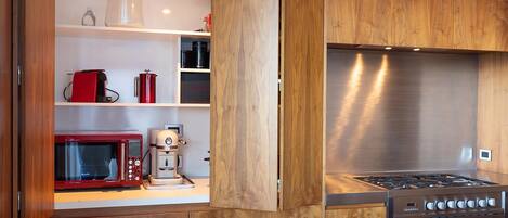 Una cocina moderna con armarios de madera, estufa de acero inoxidable, microondas y cafetera.