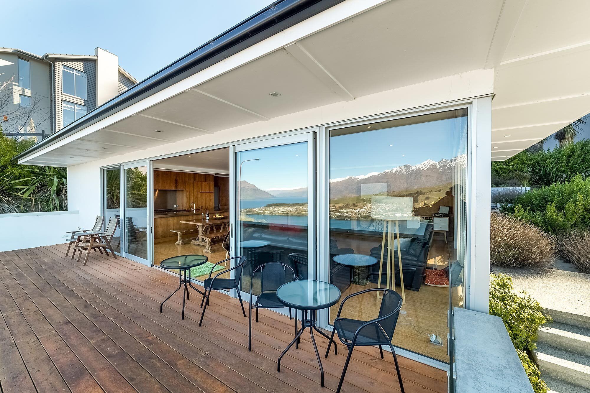 Une maison moderne dotée d’une terrasse, de portes coulissantes en verre et offrant une vue sur les montagnes.