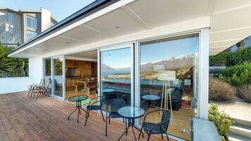 Une maison moderne dotée d’une terrasse, de portes coulissantes en verre et offrant une vue sur les montagnes.