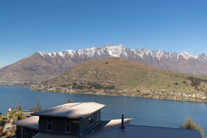 Una casa con vistas a un lago y montañas nevadas al fondo.