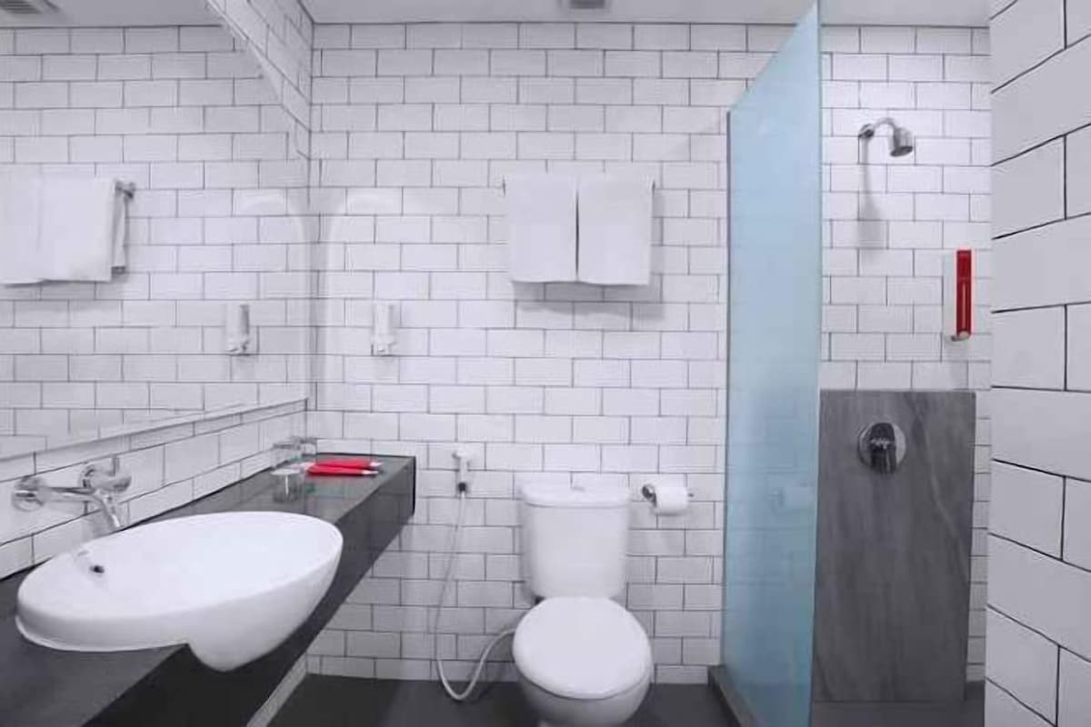 Un baño moderno con lavamanos, inodoro y zona de ducha blancos.