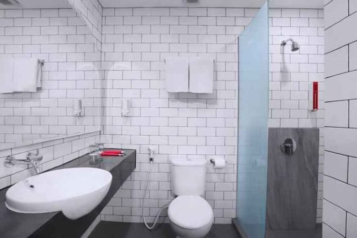 A modern bathroom with a white sink, toilet, and a shower area.