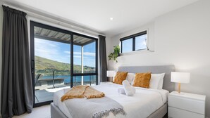 Een moderne hotelkamer met een groot bed, een nachtkastje, een raam met uitzicht op de heuvels en een balkon.