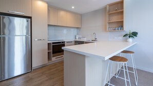 Een moderne keuken met een roestvrijstalen koelkast, een inbouwoven en een groot kookeiland met barkrukken.
