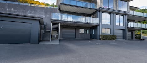 A modern two-story house with a garage, a covered driveway, and a balcony.