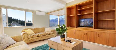 A modern living room with a sofa, coffee table, and wooden shelving unit with a television.